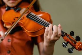 Enfant tenant un violon en petite taille pendant un cours de musique